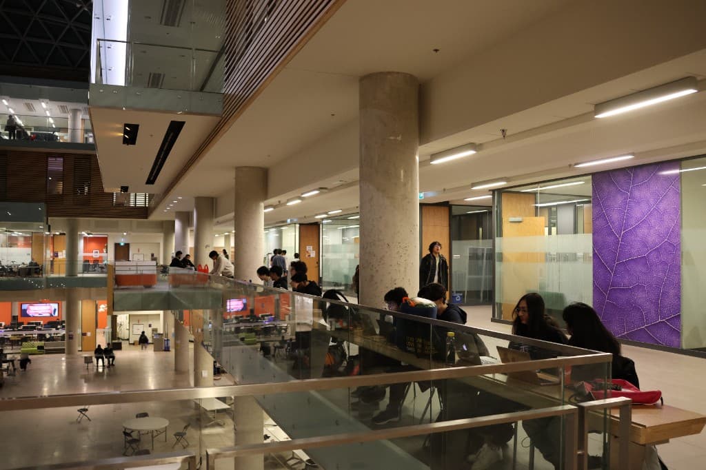 Students collaborating on laptops in a modern atrium