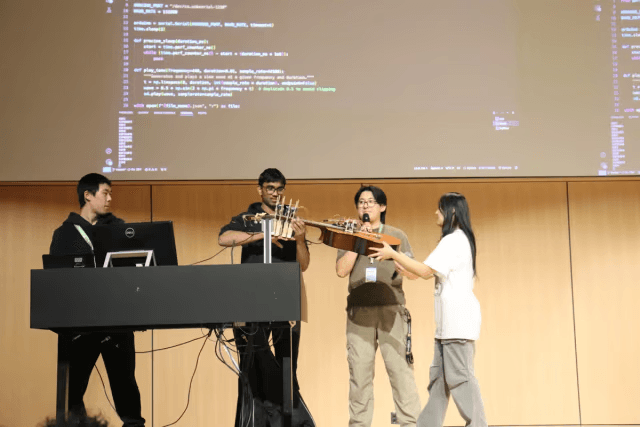 A team demoing a hardware guitar project on stage