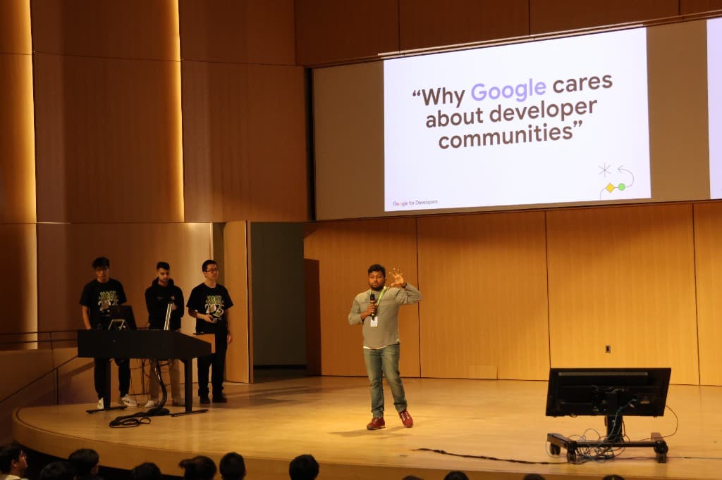 A speaker presenting on stage at a developer community event